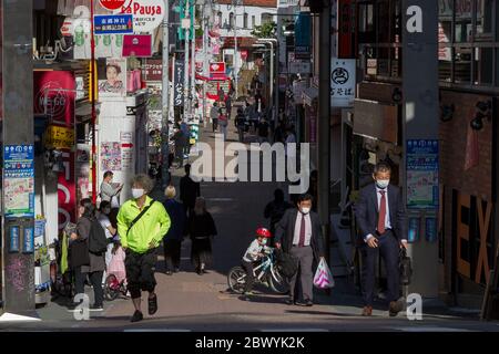 Menschen mit chirurgischen Masken in einer viel ruhigeren als sonst üblichen Takashita Dori in Harajuku, Tokio, Japan. Stockfoto