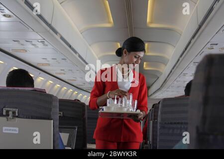 Ein Kabinenpersonal sammelt gebrauchter Wasserglas in einem Best Airways Flugzeug. Bangladesch Stockfoto
