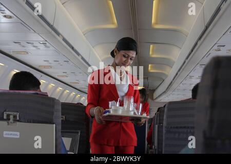 Ein Kabinenpersonal sammelt gebrauchter Wasserglas in einem Best Airways Flugzeug. Bangladesch Stockfoto