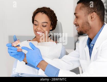 Schwarz schöner Mann Zahnarzt zeigt weiblichen Patienten Kunststoff Kiefer Stockfoto