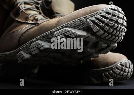 Foto von braunen Wildleder Militär taktischen Stiefel mit Protektor Textur stehend auf schwarzer Oberfläche Hintergrund Nahaufnahme. Stockfoto