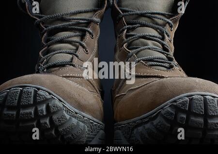 Foto von braunen Wildleder Militär taktische Stiefel auf schwarzer Oberfläche Hintergrund Vorderansicht stehen. Stockfoto
