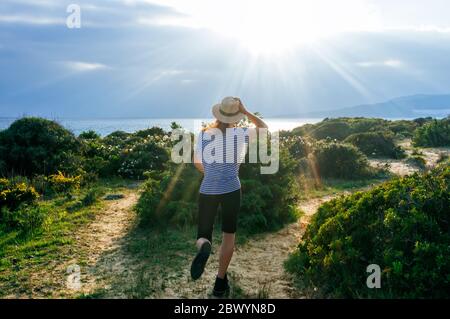 Junge Frau, die die Natur genießt. Glückliches Mädchen, das bei Sonnenuntergang im Feld spazierengeht. Schöner Frühlingstag auf dem Feld. Stockfoto