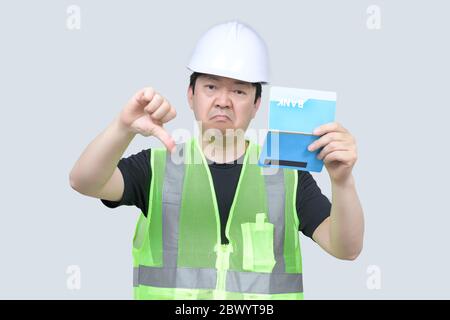 Ein Ingenieur mittleren Alters aus Asien, der ein Bankpassbuch auf grauem Hintergrund in der Hand hält. Stockfoto