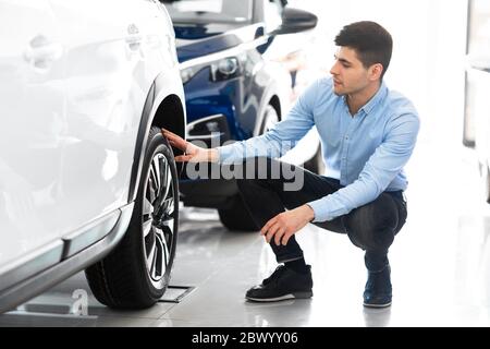 Mann, der die Felgen und Reifen des Autorads überprüft Stockfoto