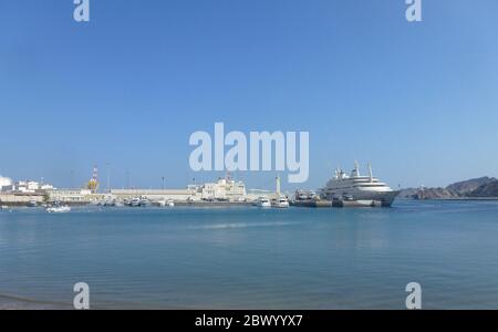 Ein Schiff legt am Hafen an. Muscat, Omans Hafenhauptstadt, liegt am Golf von Oman, umgeben von Bergen und Wüste. Oman, offiziell das Sultanat Oman, ist ein Land an der südöstlichen Küste der Arabischen Halbinsel in Westasien. Die Geschichte reicht bis in die Antike zurück und verbindet Hochhäuser mit gehobenem Shopping Stockfoto