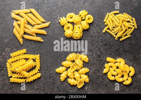 Verschiedene Arten von rohen italienischen Pasta auf schwarzem Tisch. Draufsicht. Stockfoto