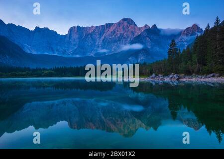 Spektakulärer, schöner Sonnenaufgang über dem alpinen See Laghi di Fusine in den Julischen Alpen in Italien Stockfoto