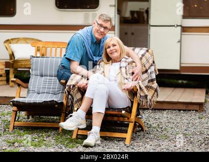 Ältere Familie auf Liegestühlen in der Nähe Wohnmobil in der Landschaft ausruhen Stockfoto
