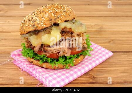 Hag braten Sie Fleisch-Sandwich mit apfelsoße und Salat in einer mit Saatgut bedeckten Brötchen auf Holzgrund Stockfoto