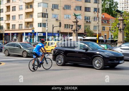 Einsamer Radfahrer, der gefährlich an der verkehrsreichen Ampelkreuzung in Sofia, Bulgarien, Osteuropa, Balkan, EU wartet Stockfoto