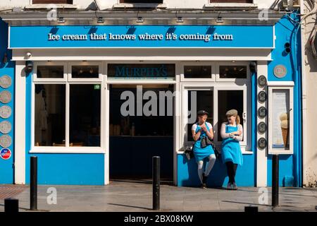 Murphy's Eiscrememitarbeiter warten auf Kunden und bieten Touristen auf der Main Street in Killarney, County Kerry, Irland, kostenlose Eisproben an Stockfoto