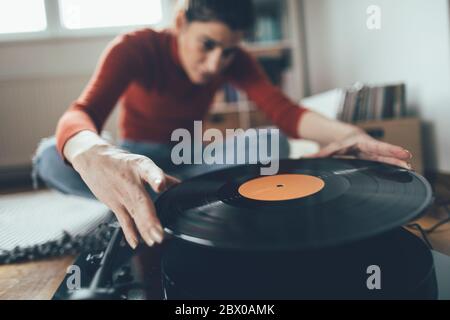 Lächelnde Frau spielt Lieblings-Vinyl-Schallplatte auf Plattenspieler Stockfoto