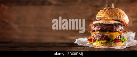 Double Beef Burger mit Käse, Spiegelei, Speck, Salat und Paprika Stockfoto