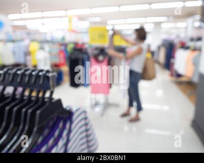 Supermarkt verwischen Hintergrund. Verschwommene Shopping-Frau mit hängenden Kleidern im Einkaufszentrum. Stockfoto