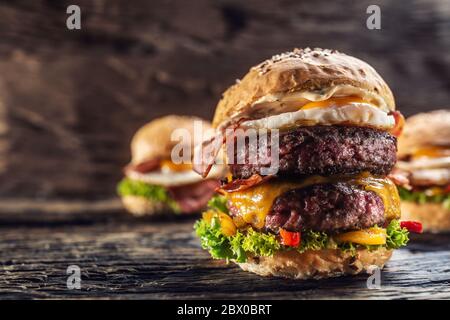 Köstlicher Double Beef Burger mit geschmolzenem Käse in einer Vintage-Umgebung mit zwei weiteren Burgern im Hintergrund Stockfoto