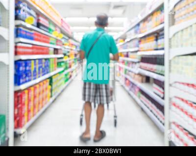 Supermarkt verwischen Hintergrund. Verschwommene Innenansicht mit einem Einkaufsmann auf dem Gang zwischen den Produktregalen im Einkaufszentrum. Stockfoto