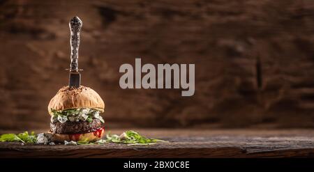 Rinderburger mit Rucola, Blauschimmelkäse und preiselbeersaft mit einem von oben erstochen Vintage-Messer Stockfoto