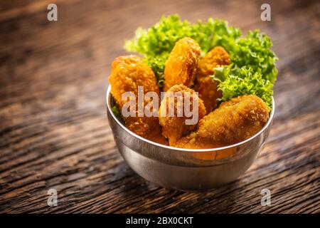 Hühnchen Nuggets mit Salat in einer Metallschüssel auf einer rustikalen Holzoberfläche Stockfoto