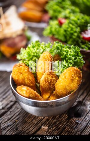 Hühnchen Nuggets mit Salat in einer Metallschüssel auf einer rustikalen Holzoberfläche Stockfoto