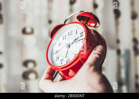 Ursache Zeit, Ruhezeit - EIN Mann hält einen Wecker und zeigt Zeit - Konzept - nicht Zeit umsonst verschwenden Stockfoto