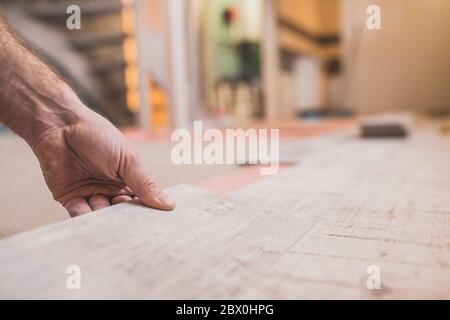 Nahaufnahme der Hand des Meisters verbindet Laminatschloss beim Verlegen von Bodenbelägen Stockfoto