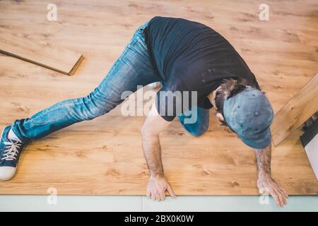 Der Erbauer ist bei der Verlegung Laminat im Zimmer - Reparatur und Nacharbeit eingerückt Stockfoto