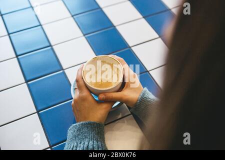 Das Mädchen hält eine Tasse mit betrunkenem Kaffee. Ihre Besprechung oder Kaffeepause endete. Stockfoto