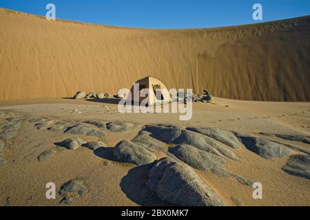 Camping im windschatten einer riesigen Sanddüne. Wüstensafari mit Geländewagen an der Skeleton Coast von Namibia, Südwestafrika. Stockfoto