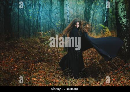 Geheimnisvolle Frau, die im magischen Wald spazierengeht. Fantasy und Gothic Stockfoto