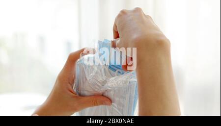 Crop Frau unter medizinischen Gesichtsmaske aus Paket in der modernen Klinik Stockfoto