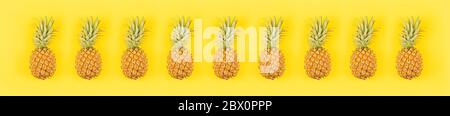 Frische Ananas auf gelbem Hintergrund. Draufsicht, Mockup, Schablone, Overhead. Sommerkonzept. Kreatives, flaches Design. Horizontales langes Banner für Webdesign Stockfoto