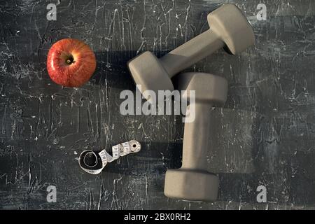 Apples Meter Tape und Hanteln auf grauem Hintergrund-Draufsicht Stockfoto