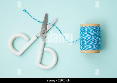 Eine niedliche kleine Schere, die versuchen, Faden zu schneiden. Stockfoto
