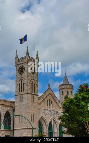 Bridgetown, Barbados, Karibik - 22. September 2018: Parlamentsgebäude mit Flagge und Uhrturm. Weiße Wolken am blauen Himmel. Kopierbereich. Vertikal Stockfoto