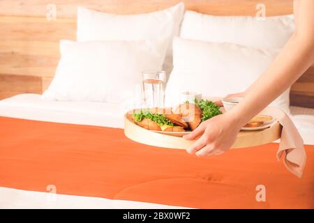 Zimmermädchen, die ein leckeres Frühstück auf dem Bett im Hotelzimmer serviert Stockfoto