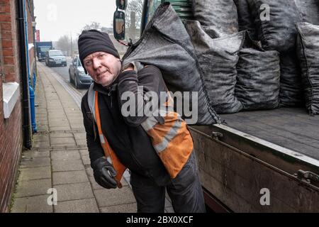 Ein Kohlenmann, der Säcke mit Hauskohle in einer Straße in Longton, Stoke on Trent, Staffordshire, England, liefert Stockfoto