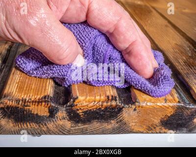 Schließen POV Schuss eines Mannes Hand mit einem nassen weichen Tuch, um die Rillen eines hölzernen Drainage Board, in ein Waschbecken zu waschen. Stockfoto