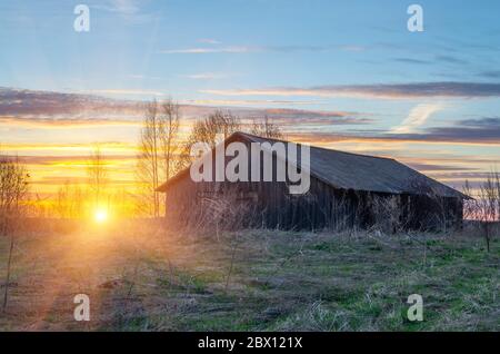 Alte Scheune auf einem Hügel und der Sonnenuntergang in einer ländlichen Dorflage Stockfoto