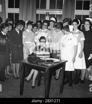 1960er Jahre, historisch, an einem Krankenpflege-Empfang, eine Gruppe von Krankenschwestern hinter der lokalen Lady Mayoress von Lewisham, die an einem Tisch im Raum sitzt, von einer Dame interviewt, die eine Audio-Rolle zu Bandspieler, South London, England, Großbritannien. Stockfoto