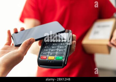 Paketzustellung wird mit kontaktloser nfc-Zahlung mit dem Telefon bezahlt Stockfoto