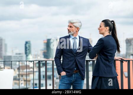 Ein Geschäftsmann und Geschäftsfrau, die auf einer Terrasse stehen und sprechen. Stockfoto