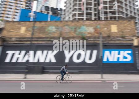 Ein Radfahrer fährt nach der Einführung von Maßnahmen, um England aus der Blockierung zu bringen, an einem „Dankeschön an NHS“-Wandgemälde in Shoreditch im Osten Londons vorbei. Stockfoto