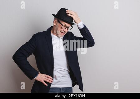 Porträt eines älteren Mannes mit Hut und Brille in einem Atelier. Stockfoto