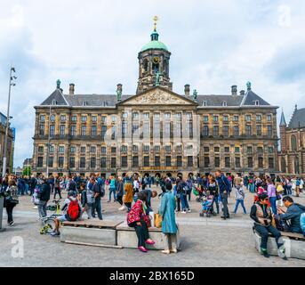 Amsterdam, 13. Juni 2019 - Touristen besuchen den Dam Platz mit im Hintergrund das ehemalige Rathaus und heute königlicher Palast im Zentrum der Stadt Stockfoto