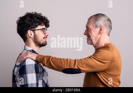 Porträt eines fröhlichen älteren Vaters und eines jungen Sohnes in einem Atelier. Stockfoto
