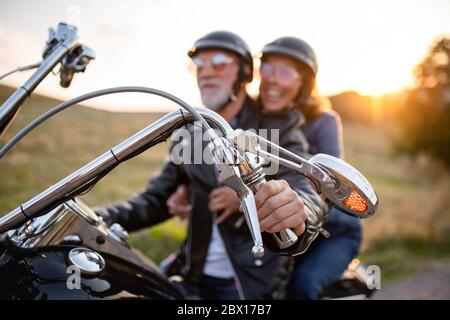 Fröhliche ältere Paare mit Motorrad in der Landschaft. Stockfoto