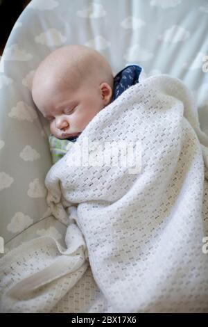 Ein neugeborener Junge schläft in einem Baby Türsteher. Foto von Sam Mellish Stockfoto