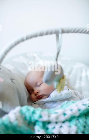 Ein neugeborenes Mädchen, das in einem Baby-Türsteher schläft. Foto von Sam Mellish Stockfoto