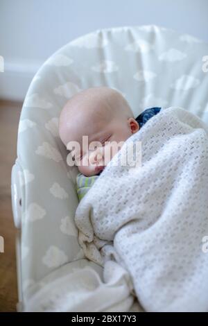Ein neugeborener Junge schläft in einem Baby Türsteher Foto von Sam Mellish Stockfoto